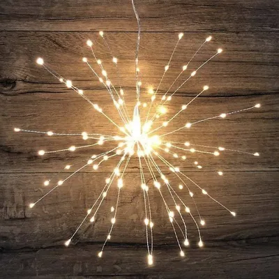 A starburst-shaped LED light decoration against a wooden background.