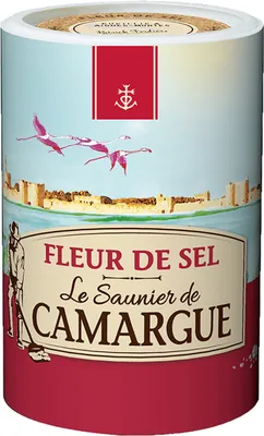 A cylindrical container of Fleur de Sel with a scenic illustration of flamingos flying over a walled city.