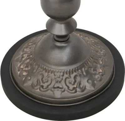 A close-up view of the base of a table, showing decorative metalwork and a black rubber ring.