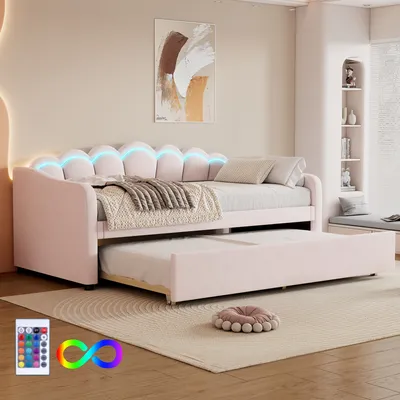 A pink upholstered daybed with a pull-out trundle bed, featuring LED lighting along the headboard, set in a bedroom.
