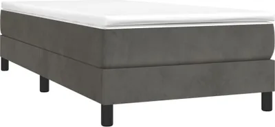 A studio shot of a dark gray box spring bed frame with a white mattress on top, set against a white background.