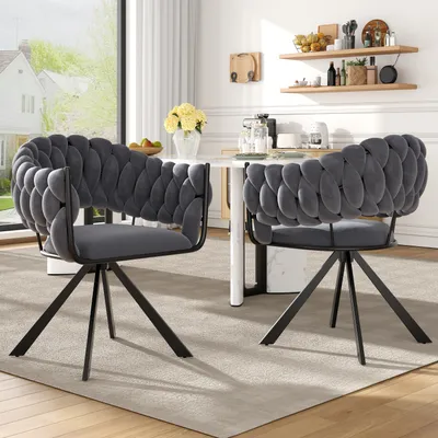 Two gray velvet dining chairs with braided backs are placed around a white dining table in a well-lit room.