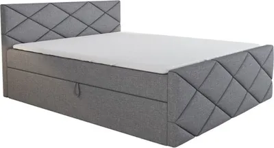 A grey upholstered boxspring bed with a mattress and a diamond-stitched headboard is shown against a white background.