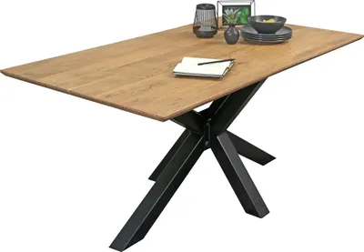 A wooden dining table with a black spider leg base, set against a white background. Decorative items are placed on the table.