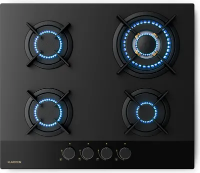 A top-down view of a black gas stovetop with four burners, three of which are lit with blue flames.