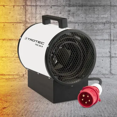 A Trotec construction heater is shown in front of a concrete wall with a warm glow on the left side.