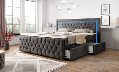A bedroom scene featuring a large upholstered bed with integrated LED lighting and storage drawers.