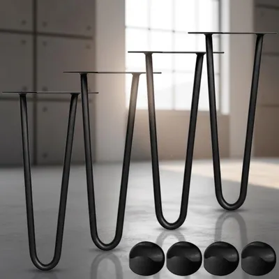 Four black hairpin legs are displayed on a concrete floor in front of a window with natural light. Four black circular caps are also visible in the foreground.