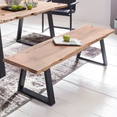 A wooden bench with a live edge sits in a dining room next to a dining table.