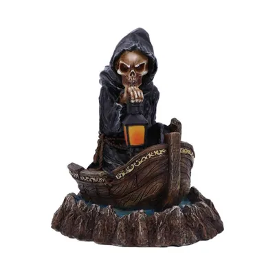 Eine Figur des Sensenmanns, der in einem kleinen Boot auf einem felsigen Untergrund sitzt.