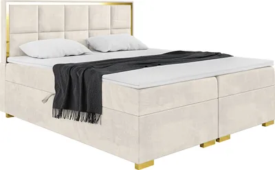 A studio shot of a boxspring bed with a headboard, mattress, and topper.