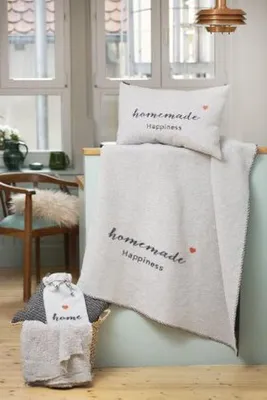 A cozy scene with a blanket and pillow on a counter, with a chair and window in the background.