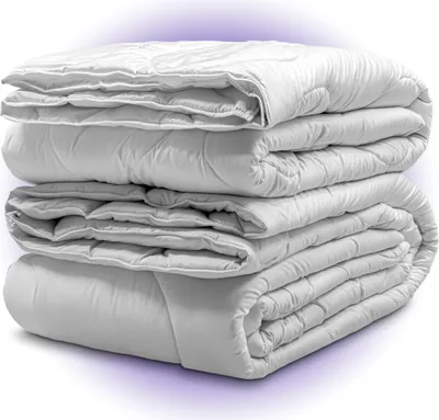 A stack of four white duvets on a white background.