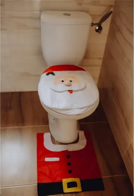A toilet with a Santa Claus themed toilet seat cover and matching floor mat.
