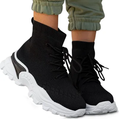 A pair of black high-top sneakers worn by a person, shown from the front-diagonal view against a white background.