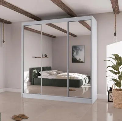 A bedroom scene with a large mirrored wardrobe reflecting the room and a bed.