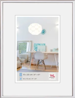 A framed picture of a desk area with a chair and a lamp.