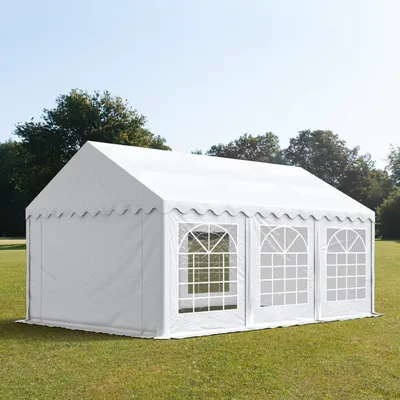A white party tent is set up on a grassy lawn with trees in the background.