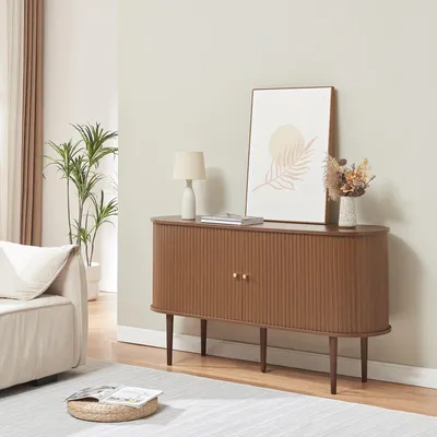 A living room scene featuring a wooden sideboard with decorative items on top, a sofa, and a plant.