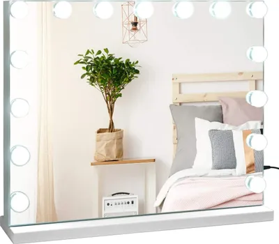 A vanity mirror with LED lights is placed on a shelf in a bedroom setting, reflecting a bed and a plant.
