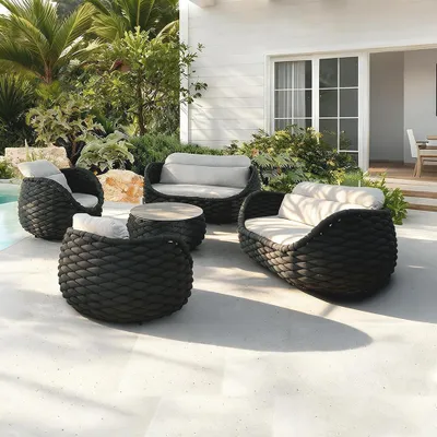 An outdoor furniture set on a patio with greenery and a building in the background.
