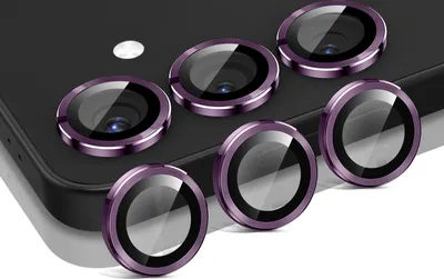 A set of six dark violet camera lens protectors arranged on a dark surface, likely a phone.