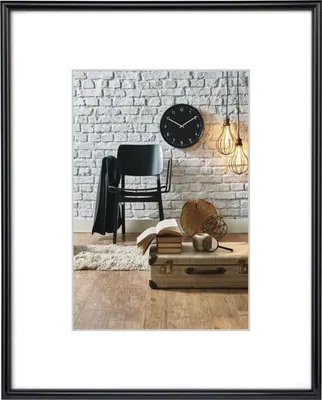 A framed picture of a vintage-style room with a chair, clock, books, and a suitcase.