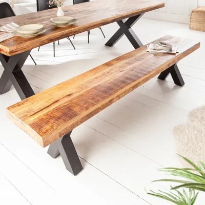 A wooden bench with black X-shaped legs is placed in front of a wooden dining table, also with black X-shaped legs.