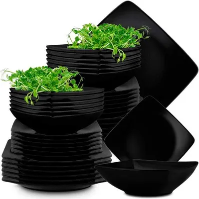 A stack of black square plates and bowls, some filled with microgreens.