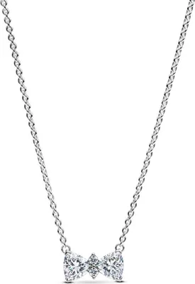 A close-up studio shot of a silver necklace with a bow-shaped pendant.