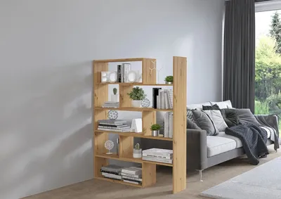 A wooden bookshelf filled with books and decorative items, placed next to a sofa in a living room.