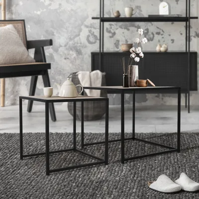 A living room scene with two nesting side tables, a chair, and decorative items.
