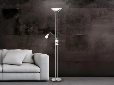 A modern floor lamp with an adjustable reading light is placed next to a light gray sofa against a dark, textured wall.