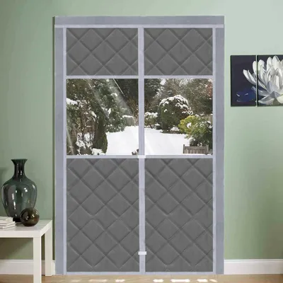 A winter scene viewed through a quilted magnetic thermal curtain on a door.