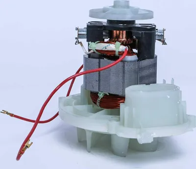 A close-up studio shot of a vacuum cleaner motor with red wires and a white plastic base.