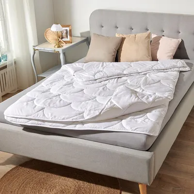 A bed with a white comforter and pillows.