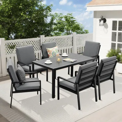 An outdoor patio set with a table and chairs, set up on a deck with a white lattice fence and greenery in the background.