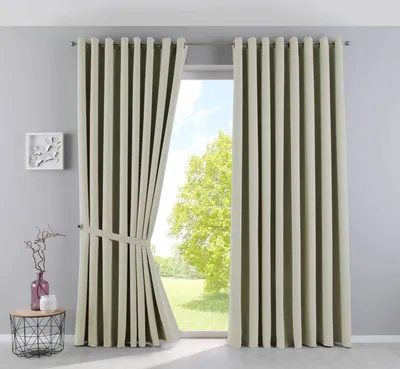 A room interior with a large window covered by beige curtains. A small side table with decorative items is placed to the left of the window.
