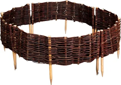 A circular garden border made of woven willow branches, supported by wooden stakes.