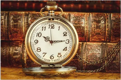 Produktbild von Wallario Wandbild Alte Taschenuhr vor antiken Büchern, Größe: 61 x 91,5 cm, Poster mit rahmenlosen Bildhalter