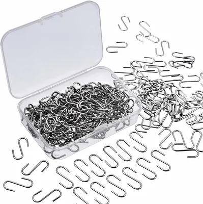 A clear plastic box filled with small metal S-hooks, with many more scattered around the box on a white background.