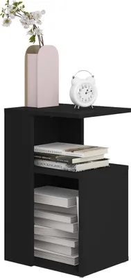 A black bedside table with books, a vase of flowers, and an alarm clock on top.