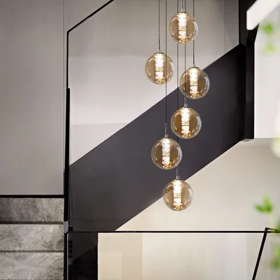 A modern staircase with a series of hanging glass pendant lights.