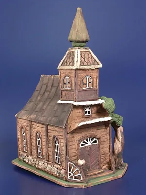 Ein handgefertigtes Keramikmodell einer rustikalen Holzkirche. Die Kirche ist detailliert gestaltet.