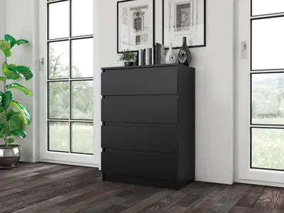 A black dresser with four drawers is placed in a room with large windows. A plant is on the left side of the dresser.