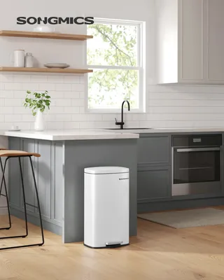 A modern kitchen setting with a white pedal trash can as the main focus.