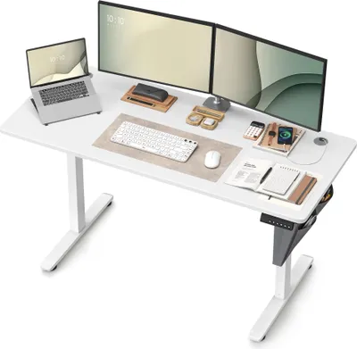 A white adjustable standing desk with a laptop, two monitors, a keyboard, and a mouse.