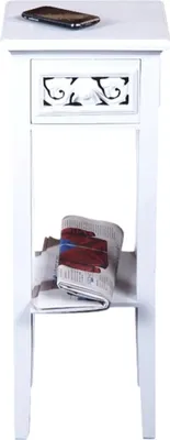 A white side table with a drawer and a shelf, holding a folded newspaper and a mobile phone on top.