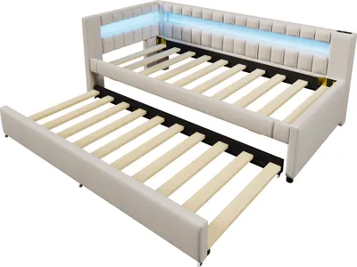 A beige upholstered daybed with a pull-out trundle bed underneath, featuring blue LED lighting along the headboard.