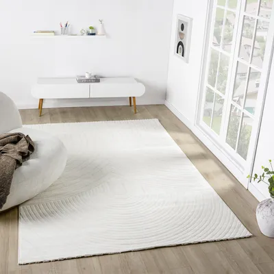 A modern living room with a white rug, a white media console, and a large window.
